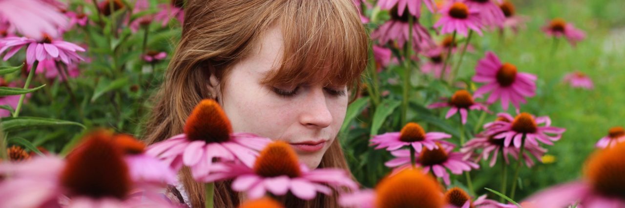 How Mixed Episodes in Bipolar Disorder Have Landed Me in Hospital woman sitting in field of pink flowers looking melancholy