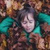 Boy with eyes closed laying in a pile of leaves