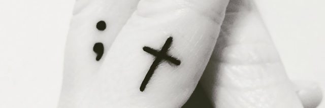 black and white photo of semicolon and cross tattoo on woman's fingers