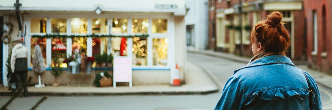 woman looking at shop across street with shop and street out of focus
