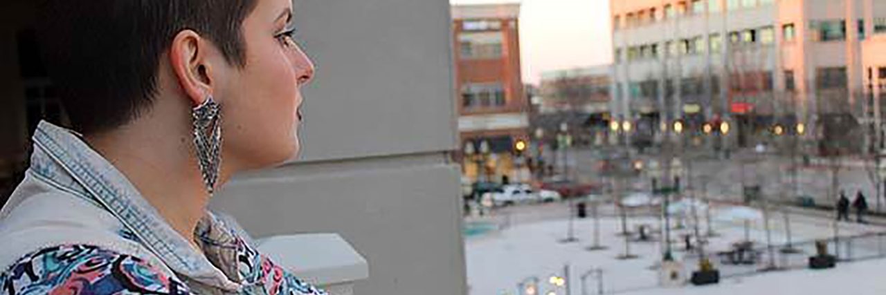 My Journey to Self-Love as a Woman on the Autism Spectrum Elizabeth standing on a balcony watching people below.