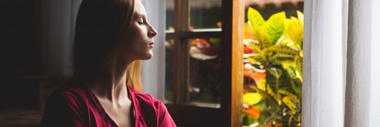 How Meditation Helped Me After a Traumatic Brain Injury woman sitting at window eyes closed meditation or mindfulness