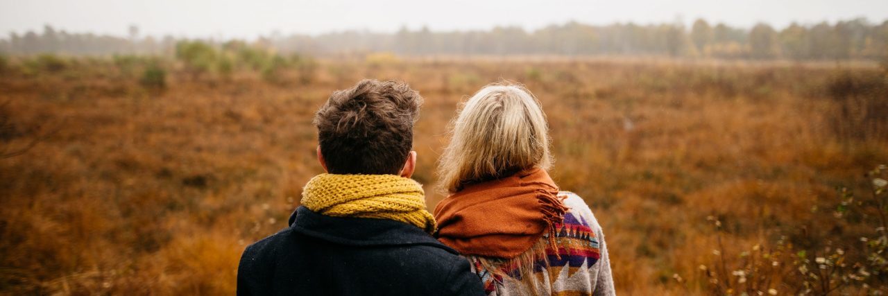 couple embracing in front of misty field in fall or winter