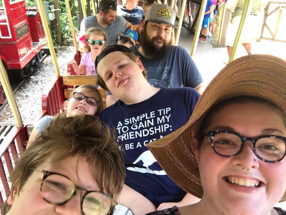 mother riding a train at the zoo with her three children