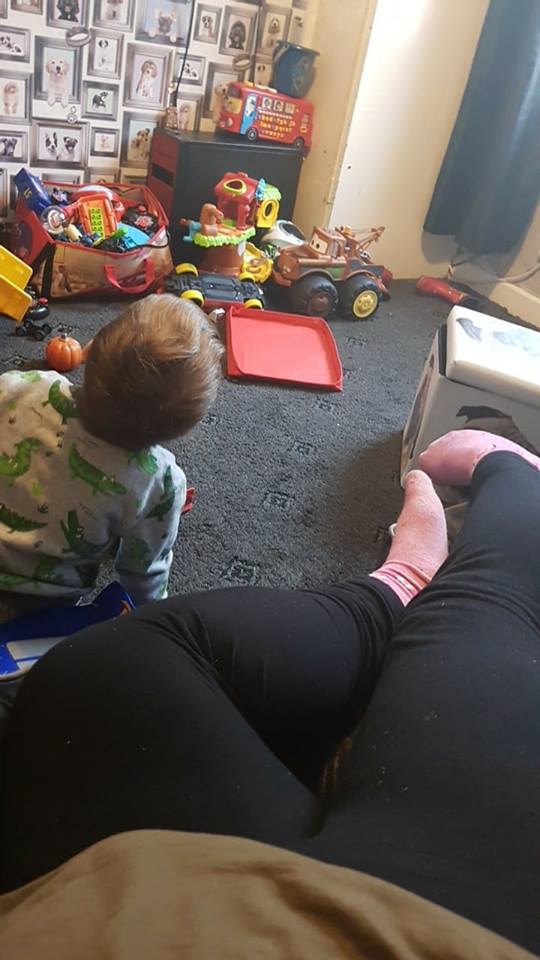 woman lying on the couch while her son plays on the floor