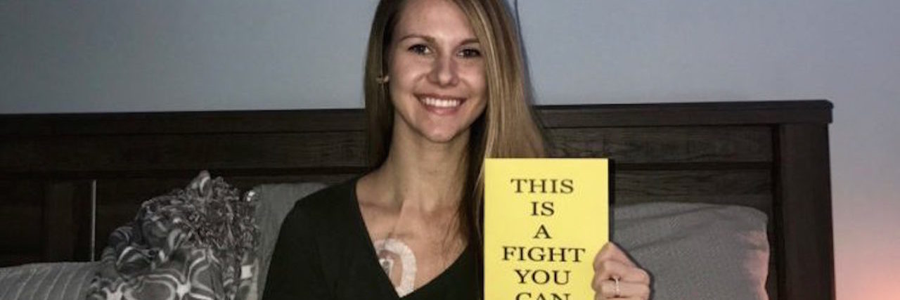 To the Woman at the Bar Who Asked, 'Is That a Port?' woman sitting on bed with port in chest holding paper that says this is a fight you can win