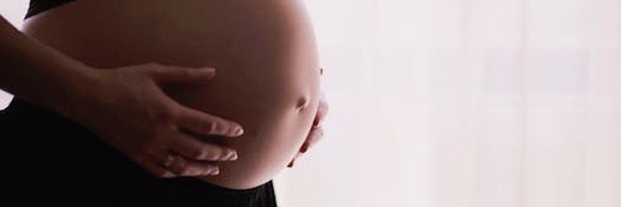 Navigating Pain Relief During Pregnancy With Fibromyalgia woman holding her pregnant belly