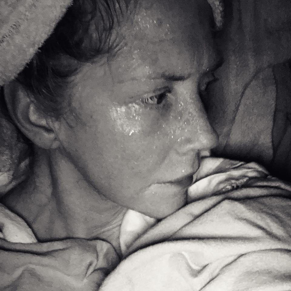 black and white photo of a woman sweating while lying in bed at night