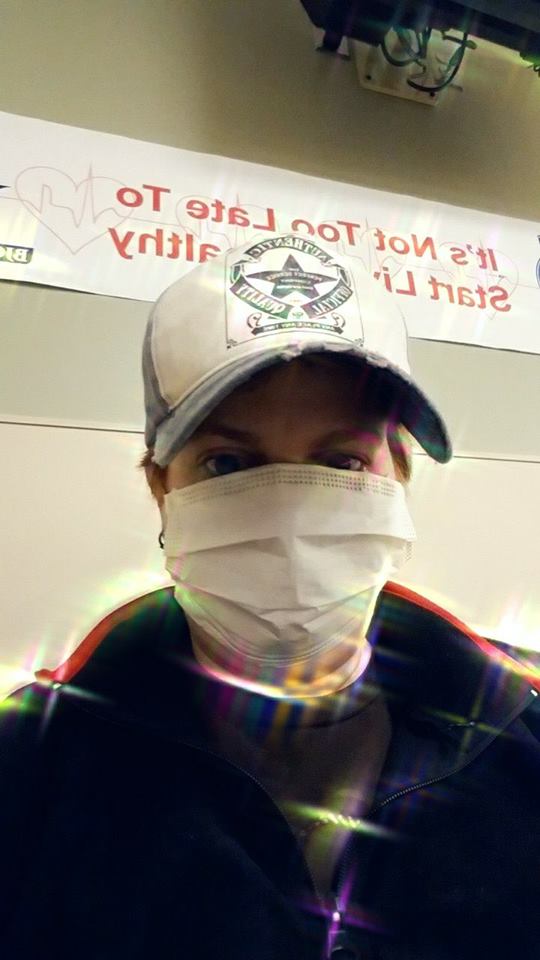 woman wearing a face mask and a baseball cap in the waiting room of the ER