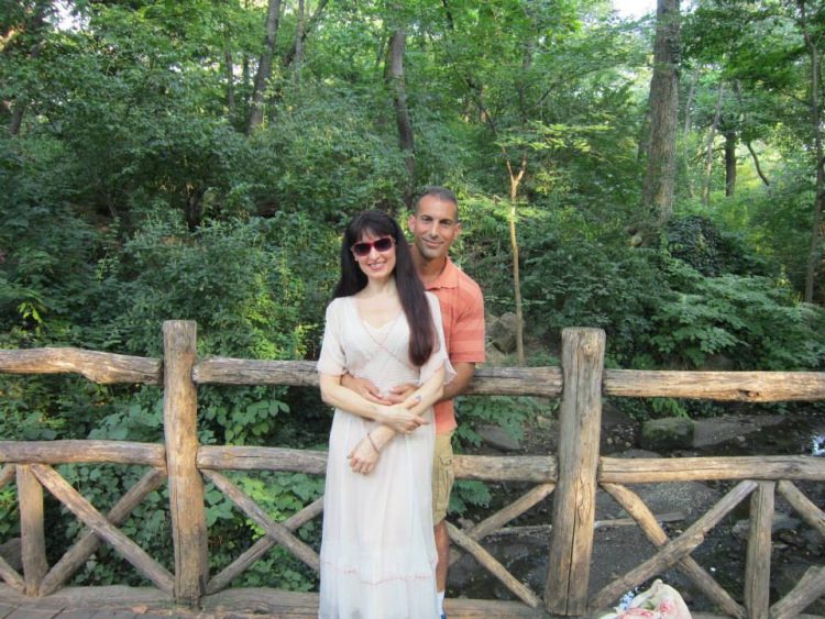 the author and her husband arm in arm with a fence and trees behind them