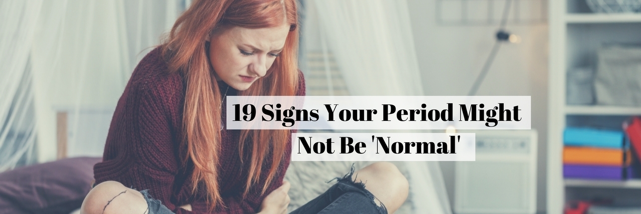 19 Signs Your Period Might Not Be 'Normal' text over woman sitting on bed holding stomach