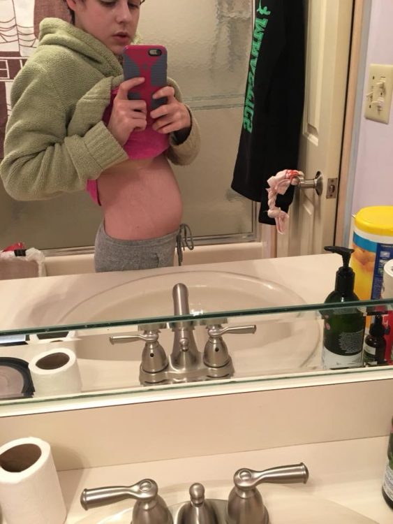 bathroom mirror selfie of girl showing bloated stomach