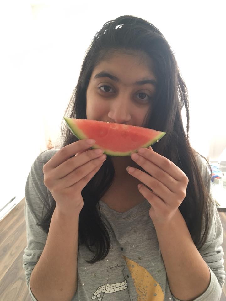 woman holding up a piece of watermelon in front of her mouth