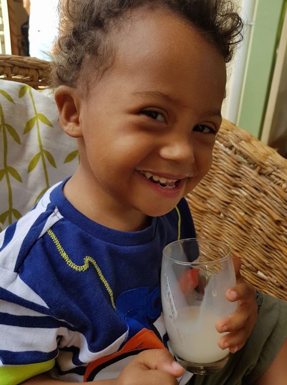 River smiling at camera holding a drinking glass 