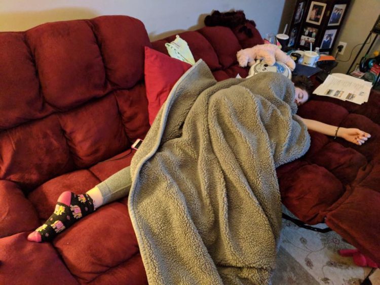 woman lying on couch under blanket