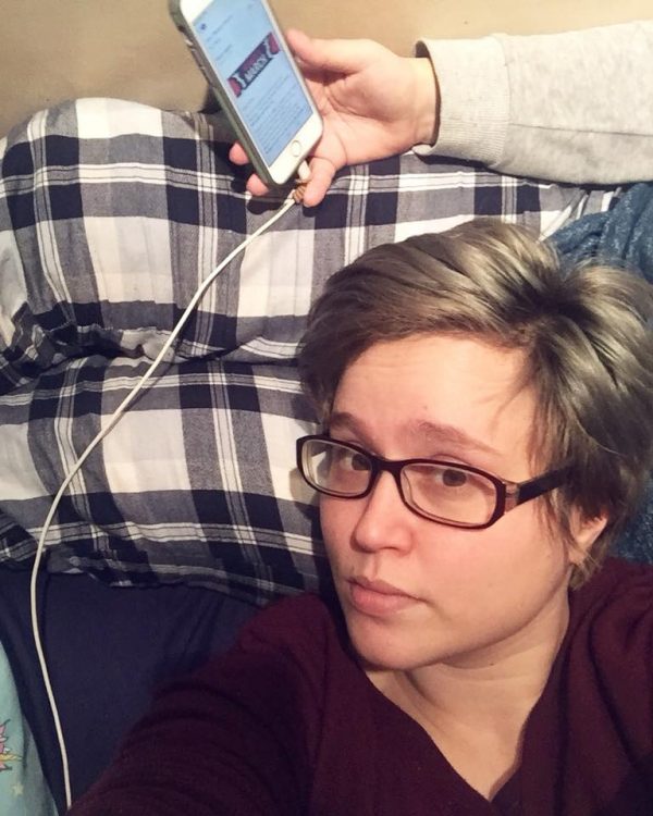 woman lying on her back with arm above her head holding phone