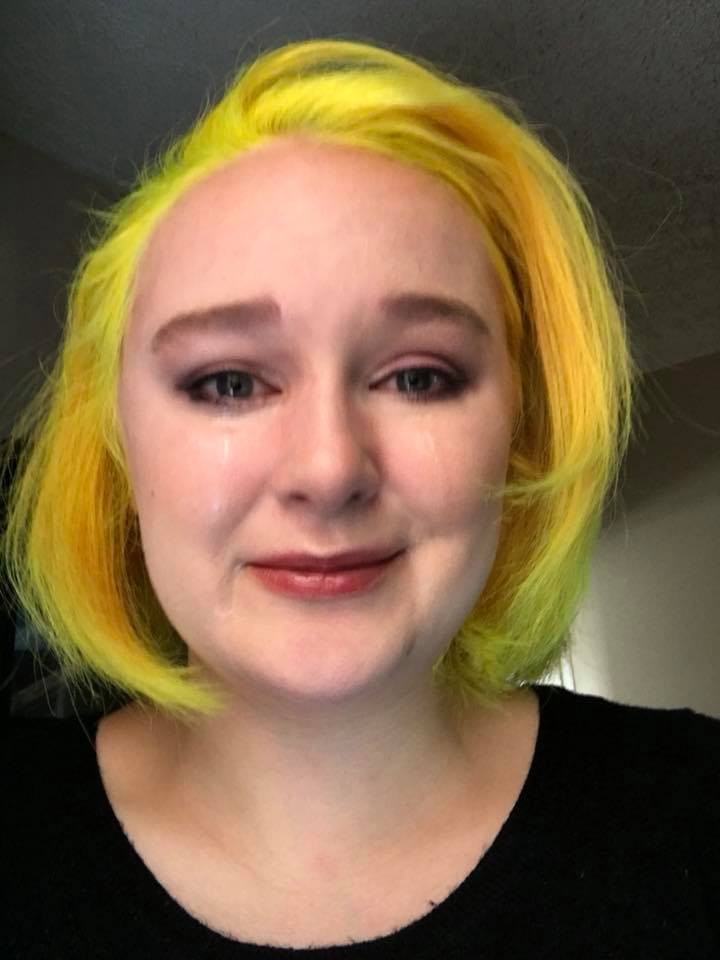 woman with yellow hair crying but trying to smile