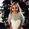 Little girl with Down syndrome standing in front of her Christmas tree and smiling for picture
