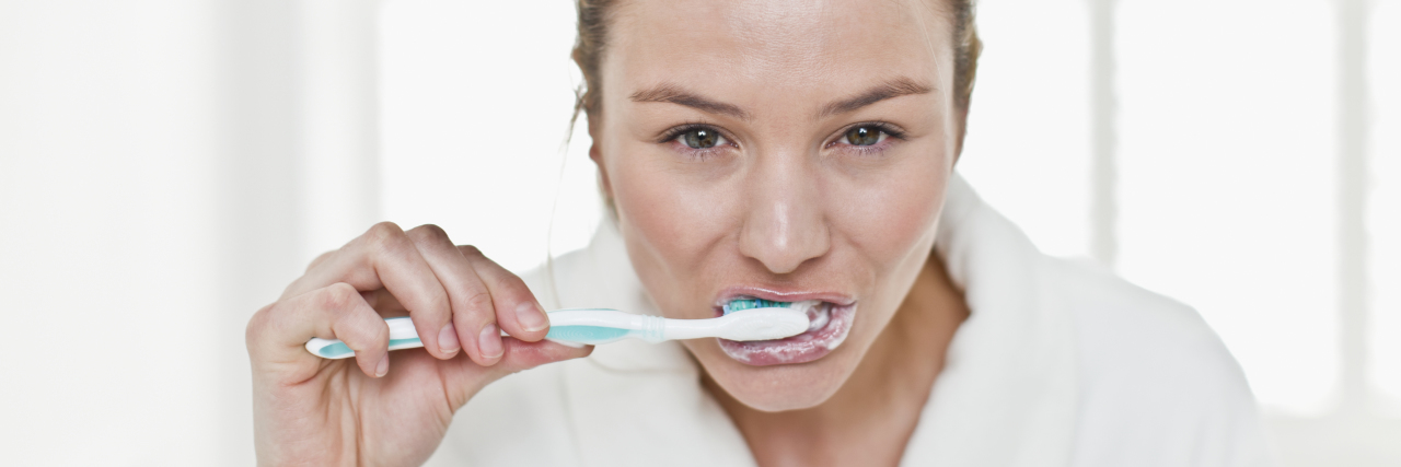 What It's Like to Brush Your Teeth With Chronic Pain Woman brushing her teeth in bathroom