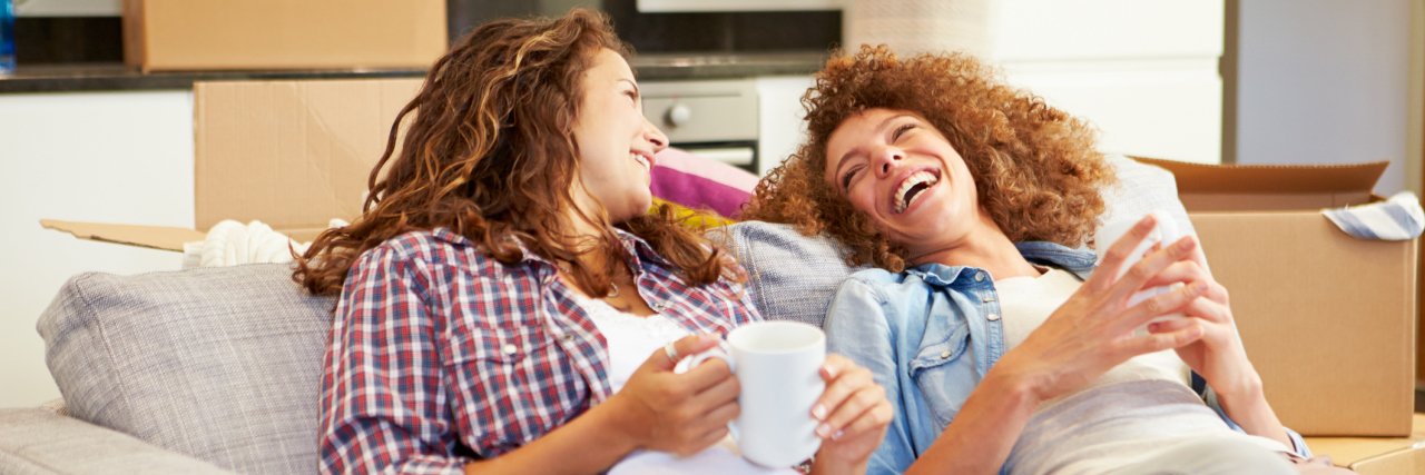 two women relaxing on a couch and laughing