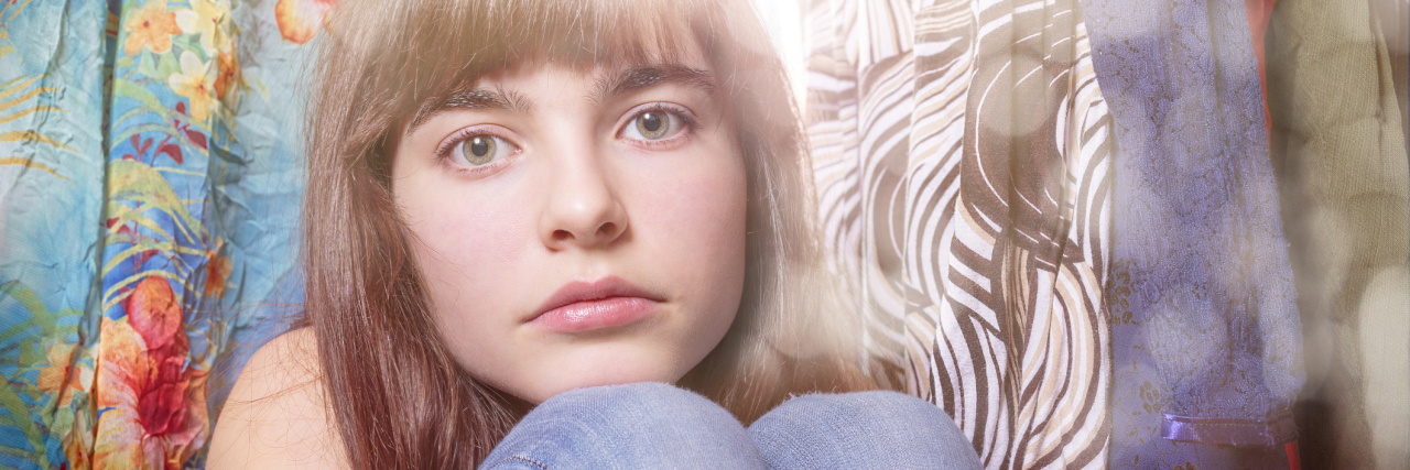 My Reality of Living With POTS A young girl sitting in a flea market, between some clothes.
