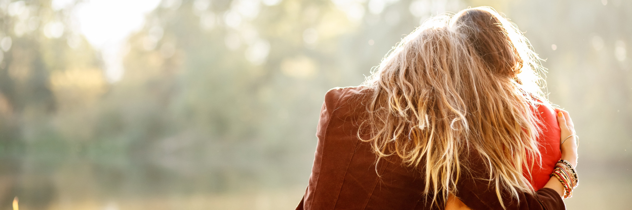 How My Girlfriend Has Supported Me as Someone With a Disability two women sitting outside and hugging