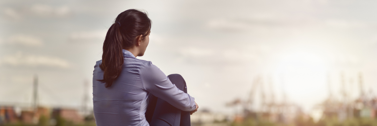 Finding Purpose in Chronic Pain With Rheumatoid Arthritis woman sitting on a bench and watching boats go by on the river