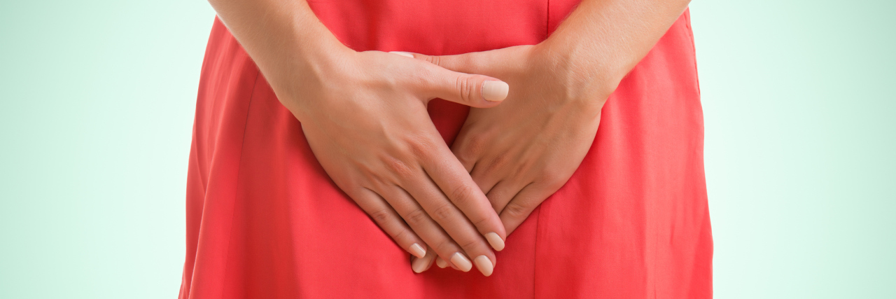 woman in a red dress holding her hands over her pelvic area