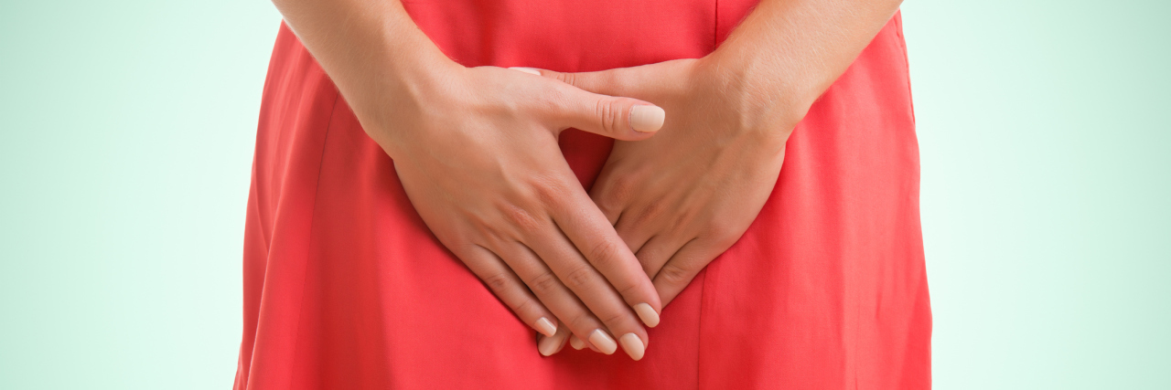 What Endometriosis Pain Feels Like for Me woman in a red dress holding her hands over her pelvic area
