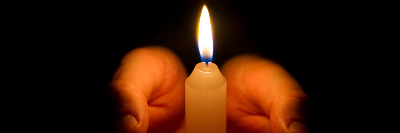 Remembering Those We've Lost on the Disability Day of Mourning Hands holding a burning candle.