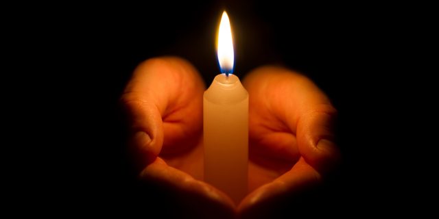 Remembering Those We've Lost on the Disability Day of Mourning Hands holding a burning candle.