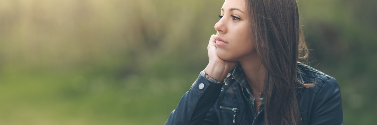 Why It's Impossible to 'Look Bipolar' Young pensive woman relaxing at the park and sitting on grass