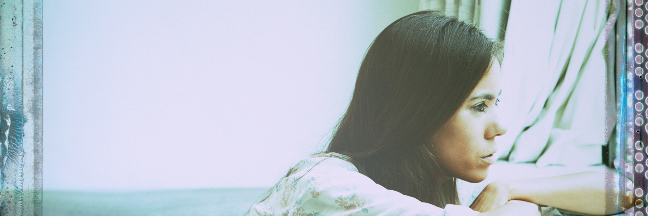 Struggling With Not Working Due to Disability Woman sitting alone looking out window.