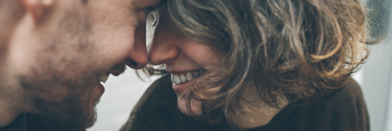 5 Ways My Partner Supports My Illness By the Things He Doesn’t Do A woman and man looking at each other, foreheads touching, with a smile.