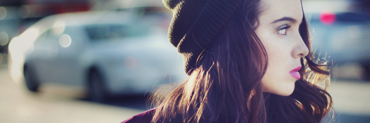 When You Have to Admit Defeat With Chronic Illness woman wearing a beanie walking outside on the street