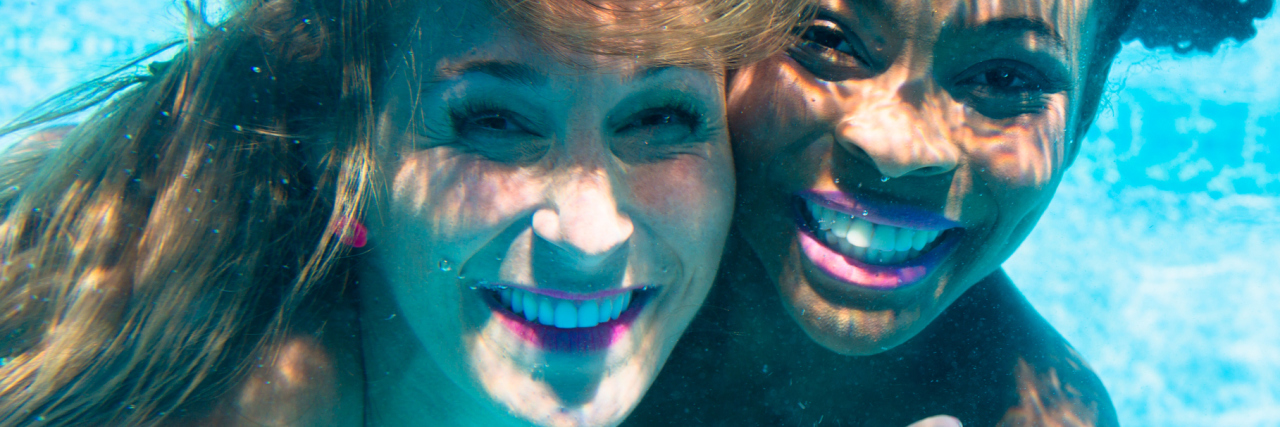 friends diving underwater together and smiling
