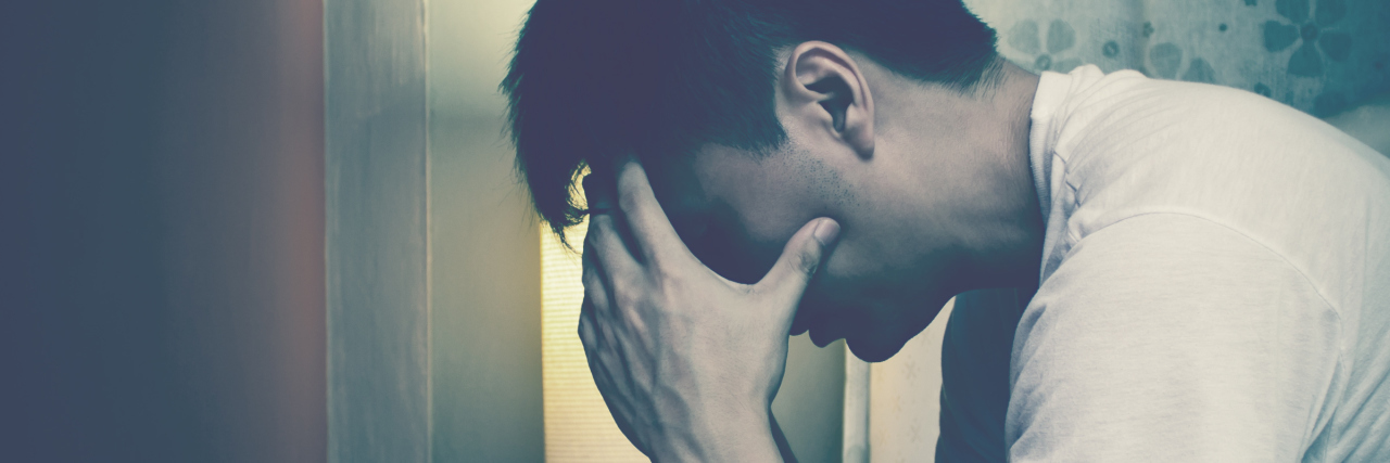 'Survival Guide' Tips for Living With Bipolar Disorder asian man sitting on bed depressed or worrying