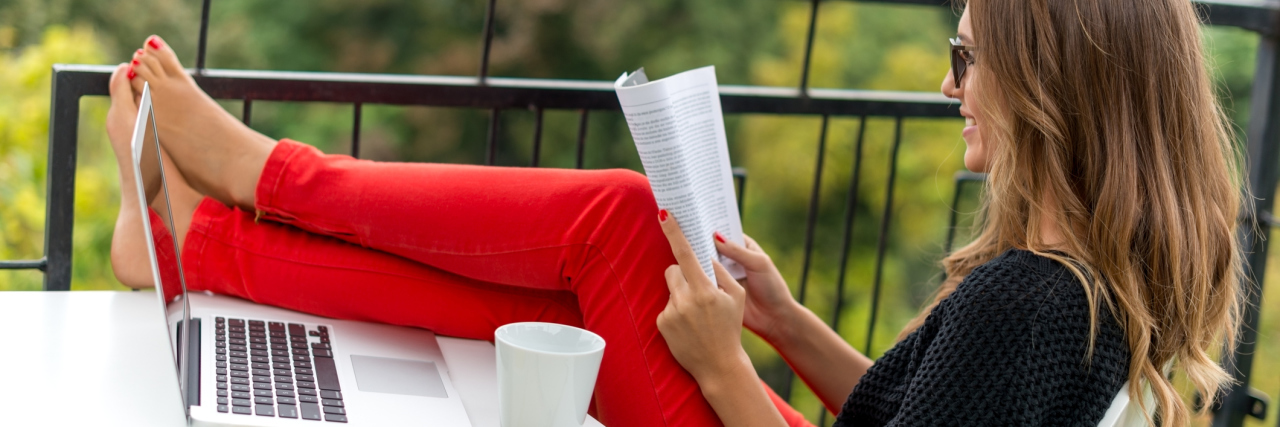 Finding Joy in Your Work When You Have a Chronic Illness Young girl reading a book and drinking coffee, while holding her feet on the table.