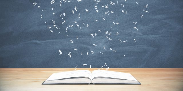 Why I'm Not Defined by My Chronic Illness A book laying on a table with letters flying above it.