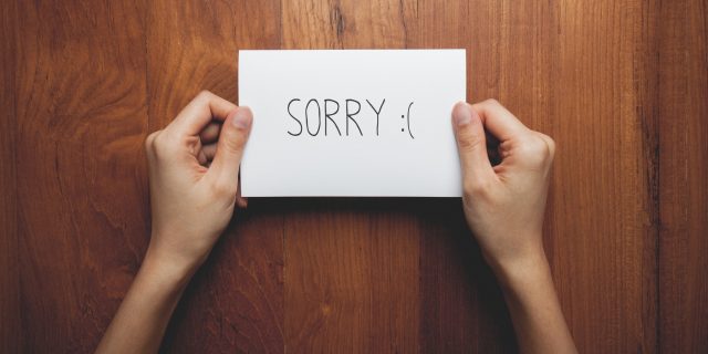 Two hands holding a note that say "Sorry."
