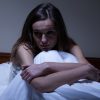 Young worried woman sitting in bed at night