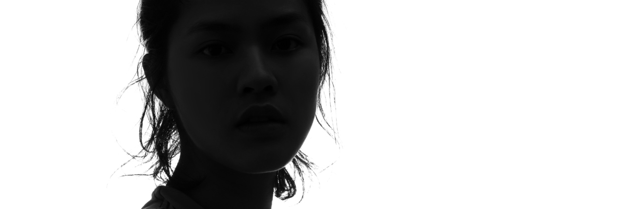 dark silhouette of a woman looking at the camera against a white background