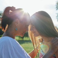 Cute pretty teen daughter with mature mother hugging in nature at sunset