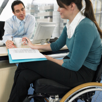 Woman in wheelchair meeting with man behind desk.