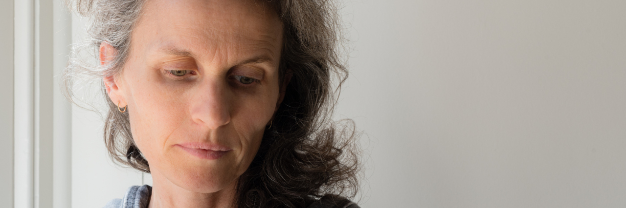 How I'm Healing After Losing My Daughter to Suicide and BPD Middle aged woman with grey hair holding green cup and looking pensive (selective focus)