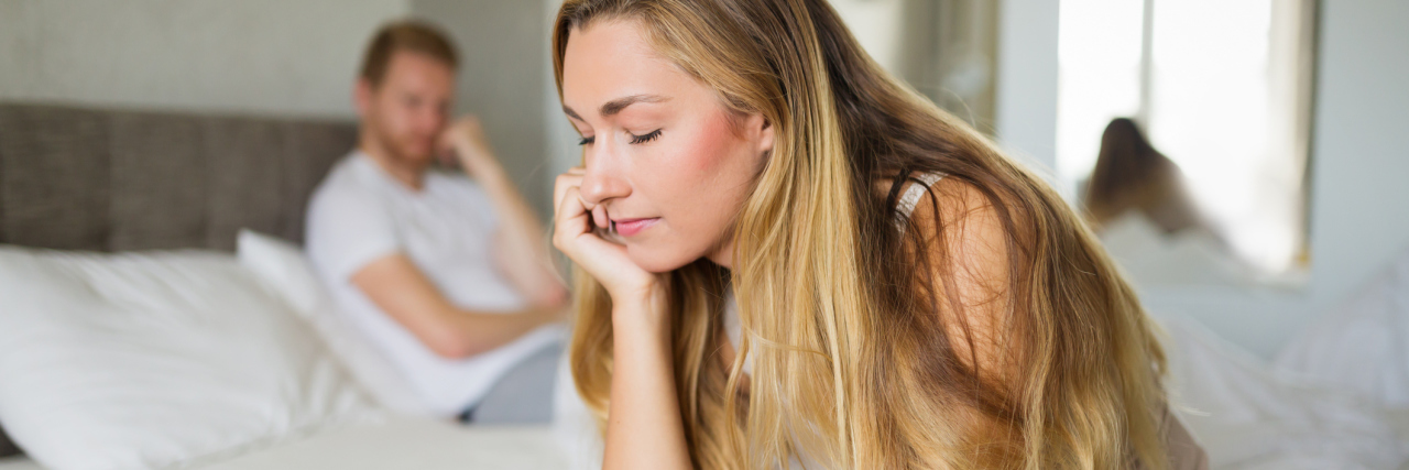 What I Want My New Boyfriend to Know About My PTSD couple in bedroom with woman sitting on edge of bed upset