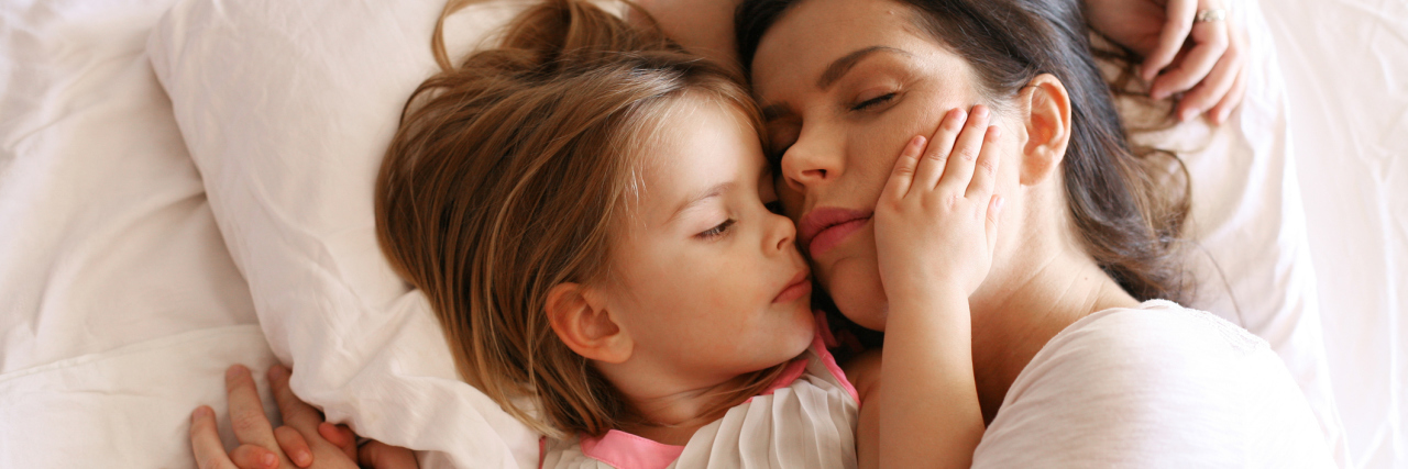mother and young daughter lying in bed sleeping