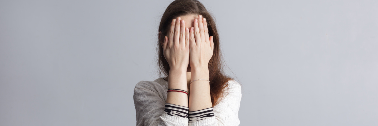 How to Cope With Excessive Sweating Because of Anxiety Girl with long hair covers his face with his hands.