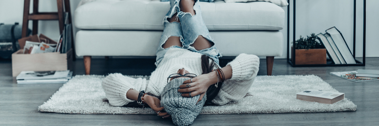 A woman with her feet up on the couch laying on the floor