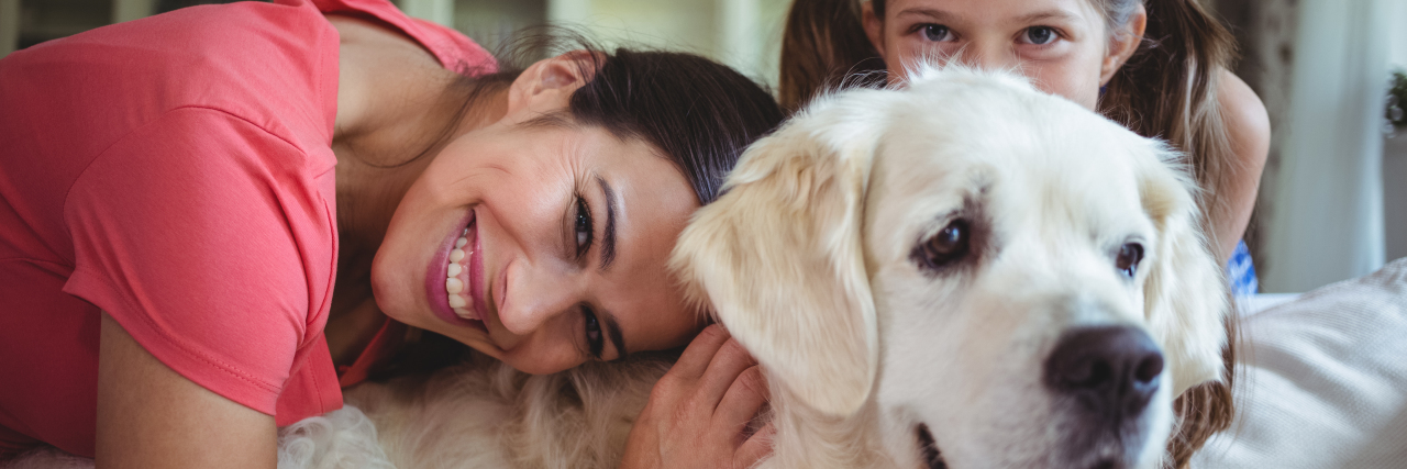 Parenting With Undifferentiated Connective Tissue Disorder Mother and daughter sitting with pet dog in living room at home